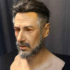 Left side of hyper realistic mask displaying natural skin folds and realistic expression.
