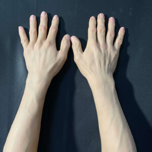 Front view of realistic silicone gloves showing lifelike skin texture and nail detail